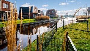A canal with modern houses, a grassy area, and a clear sky. - Spacious Holiday Home With Outdoor spa (Akkrum)