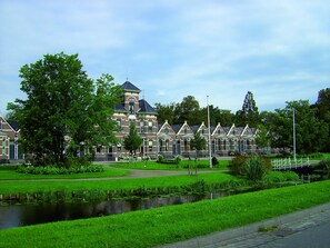 Een rij traditionele Nederlandse huizen met een centrale toren, omgeven door een verzorgd park en een gracht.