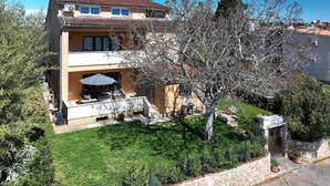 A two-story house with a balcony, a well-maintained lawn, and a stone wall. - Comfortable Apartment With Private Terrace (Fazana)