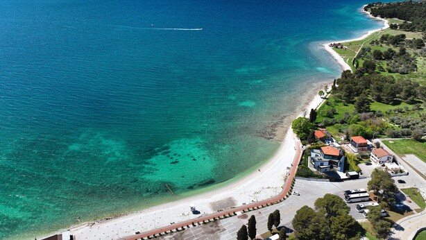 An aerial view of a coastal area with a beach, clear blue waters, and a mix of residential and commercial buildings. - Comfortable Apartment With Private Terrace (Fazana)