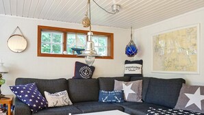 A cozy living room with a grey sofa, star-patterned pillows, a white coffee table, and a map on the wall. - 6 Person Holiday Home in Munkedal-by Traum (Munkedal)