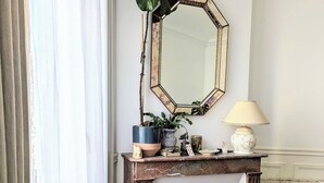 Une pièce avec une cheminée, un grand miroir et une plante en pot.