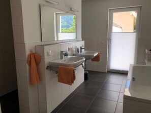 A modern bathroom with two sinks, a large mirror, and a bathtub. - Holiday Apartment Forest (Sulzburg)
