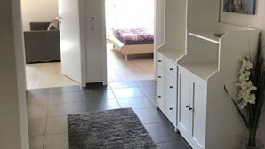 A modern bedroom with a bed, a white wardrobe, a grey rug, and a painting on the wall.