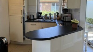 Een moderne keuken met witte kastjes, een zwart aanrechtblad en een raam dat natuurlijk licht binnenlaat.