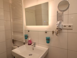 A bathroom with a white sink, a mirror, and a towel rack.