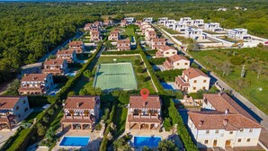 Luchtbeeld van een woongebied met huizen, een tennisbaan en een zwembad.