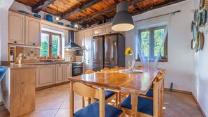 Een keuken met houten kasten, een groot eiland en een eettafel met stoelen.