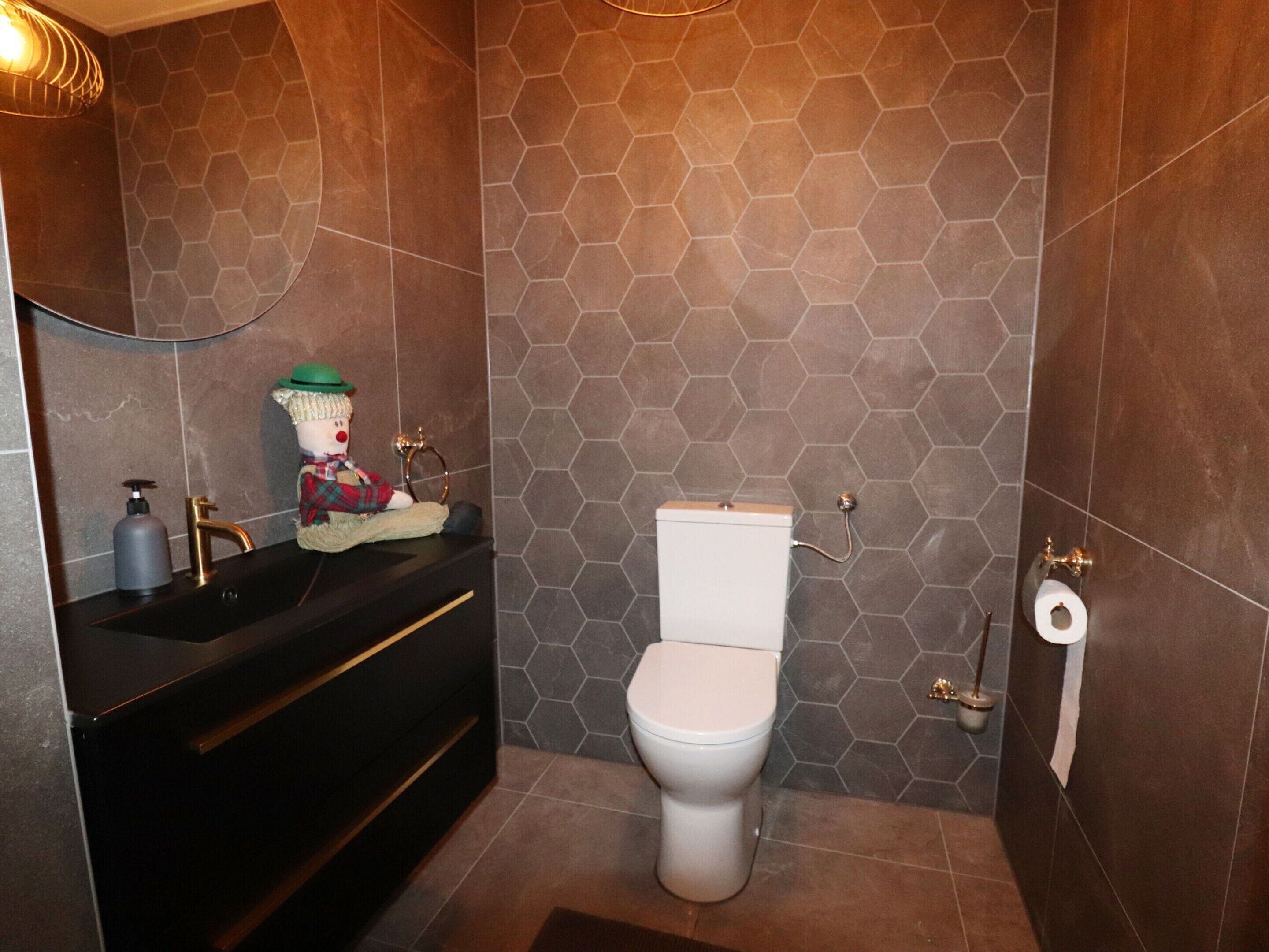 A bathroom with a black vanity, a white toilet, and a hexagonal tile wall.