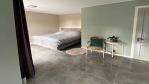 A bedroom with a bed, a chair, a small table, and a door. - Apartment in Kornhorn Near Curringherveld (Kornhorn)