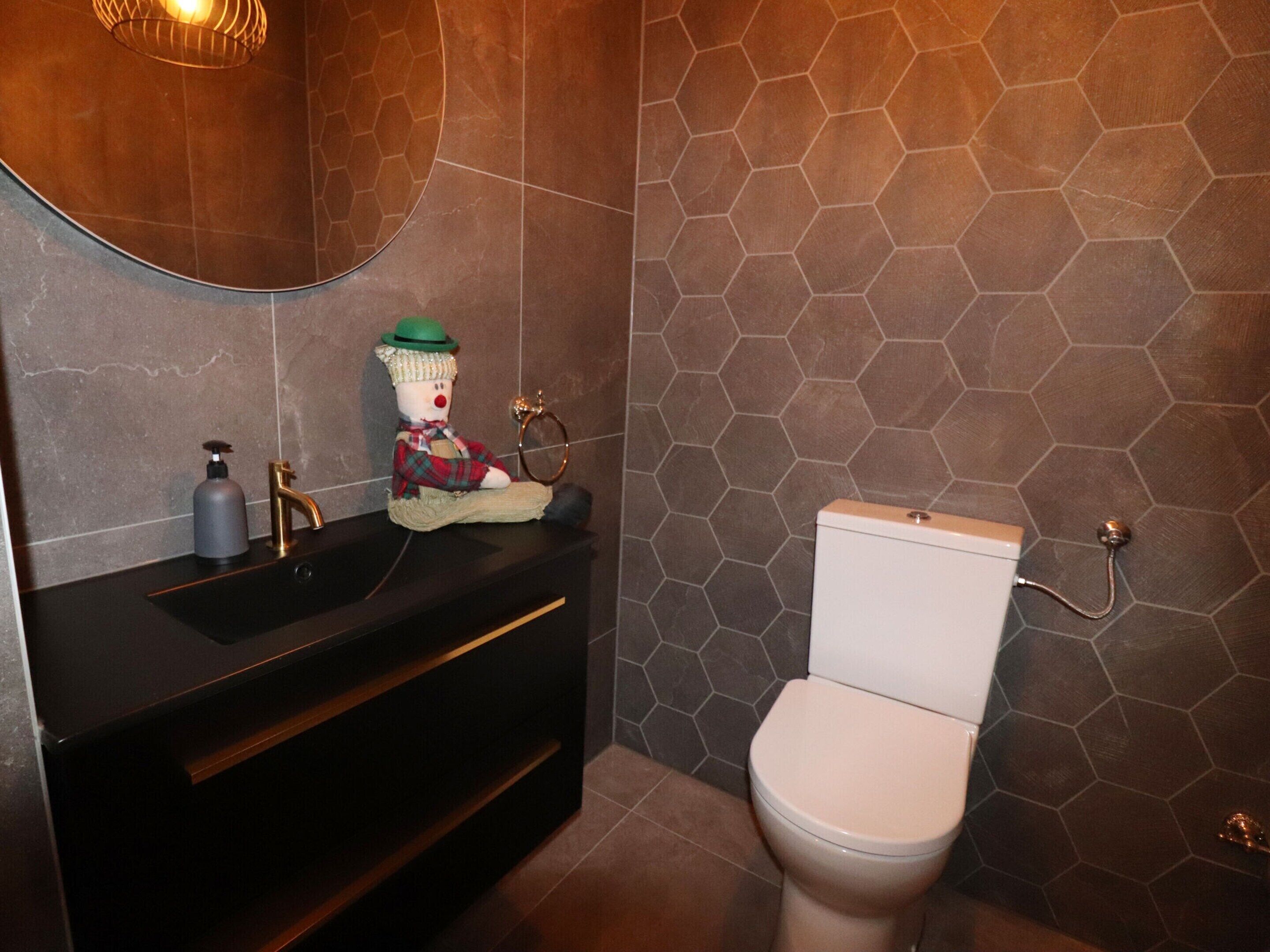 A bathroom with a black vanity, a white toilet, and a hexagonal tile wall.
