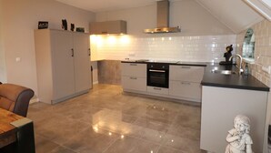 A modern kitchen with a central island, built-in oven, and a stainless steel sink. - Apartment in Kornhorn Near Curringherveld (Kornhorn)