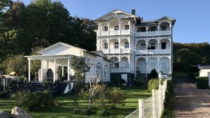 A large, multi-story white building with a central courtyard, surrounded by greenery and a paved pathway. - Sea View and Design Comfortable Vacation Home (Sassnitz)