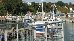 A marina with various boats docked, a pier with people, and buildings in the background. - Sea View and Design Comfortable Vacation Home (Sassnitz)