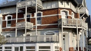 A multi-story building with a brick facade, multiple balconies, and a modern entrance.