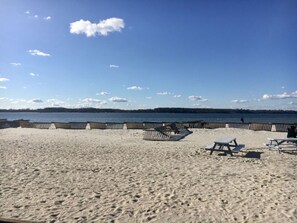A beach with a wooden fence, lounge chairs, and picnic tables. - Holiday Apartment Lust auf Laboe (Laboe)