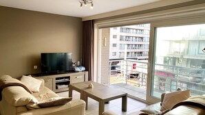Ein modernes Wohnzimmer mit einer Couch, einem Couchtisch und einem Fernseher.