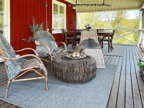 Un espace extérieur aménagé, abrité et doté de mobilier en osier, d’une table ronde et offrant une vue sur le paysage.