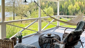 A covered outdoor area with wicker furniture, a round table, and a hammock. - 5 Person Holiday Home in Edsbruk-by Traum (Valdemarsvik)