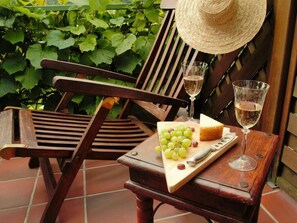 A wooden chair and table with a cheese and grapes, two wine glasses, and a straw hat. - Holiday Home Lake View (Unterwellenborn)
