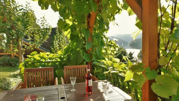 Ein Holztisch mit einer Flasche Rotwein, zwei Gläsern und einer Platte mit drei kleinen Gegenständen.