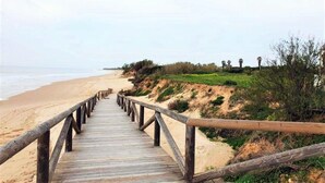 A wooden boardwalk leading to a beach with a sandy shore and sparse vegetation. - Belvilla by OYO Holiday Home in Rota (Rota)