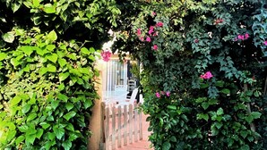 A garden entrance with a wooden gate, a paved path, and a building in the background. - Belvilla by OYO Holiday Home in Rota (Rota)