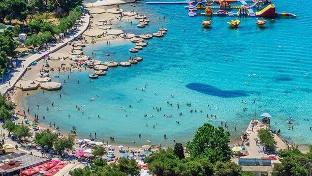 Zona costera con playa, barcos y actividades acuáticas.