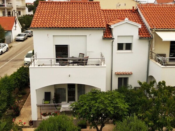 A two-story building with a red-tiled roof, a balcony with outdoor furniture, and a small garden area. - Apartment in Uberlingen (Vodice)