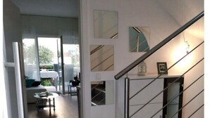 Un interior moderno con una escalera, un comedor y vistas a través de puertas de cristal.