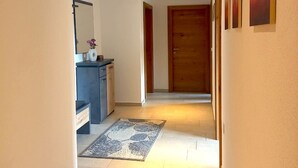 A hallway with a wooden door, a small desk with a vase of flowers, and a patterned rug on the floor. - Flat in Wagrain Near Ski Slopes (Wagrain)