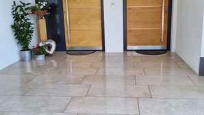 A clean, modern entrance with two wooden doors, a potted plant, and a decorative basket on the floor. - Flat in Wagrain Near Ski Slopes (Wagrain)