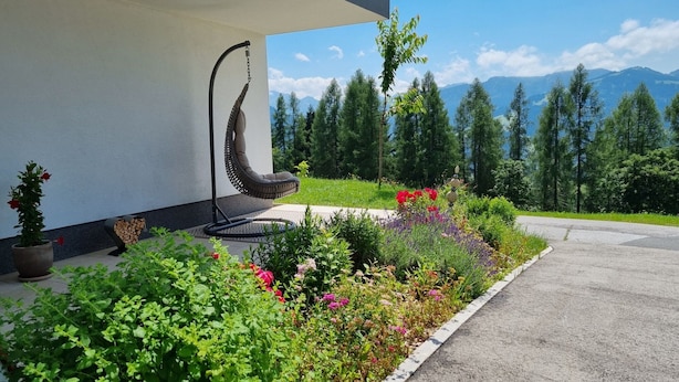 A modern building with a garden featuring a unique sculpture, a variety of plants, and a view of distant mountains. - Flat in Wagrain Near Ski Slopes (Wagrain)
