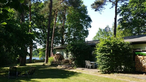 Une maison avec un porche abrité, une pelouse et des arbres.