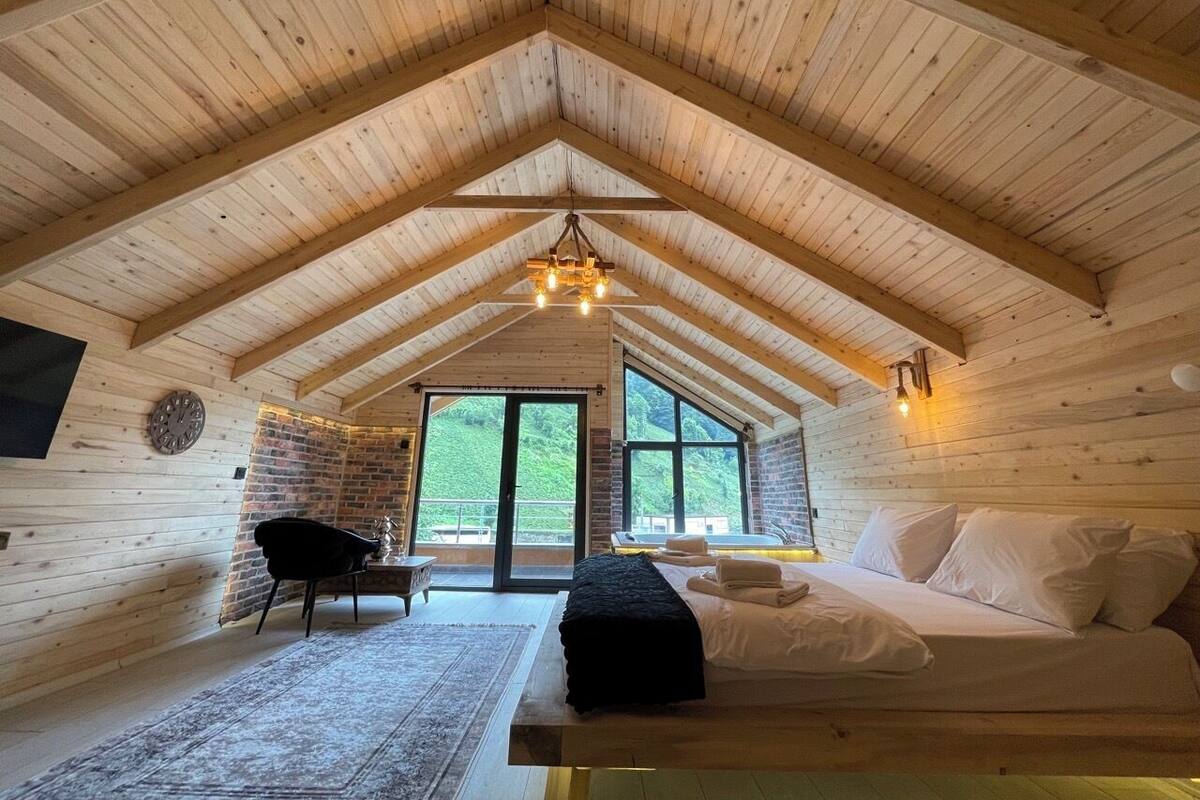 Uma cabana de madeira aconchegante com um quarto no mezanino, lareira e uma janela grande com vista para o exterior.