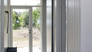 Une porte donnant sur un espace extérieur aménagé avec un banc et un paillasson.