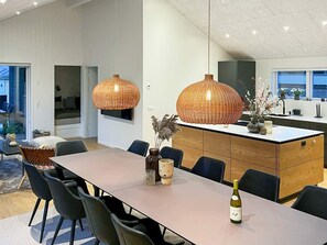 A modern kitchen with a central island, pendant lights, and a dining area with chairs and a table. - 4 Star Holiday Home in Blavand (Blavand)