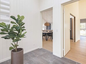 A modern interior with a potted plant, a dining area with a table and chairs, and a view into another room. - 4 Star Holiday Home in Blavand (Blavand)