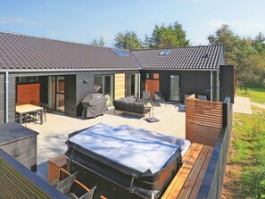 A modern house with a patio area featuring a hot tub, outdoor seating, and a barbecue grill. - 4 Star Holiday Home in Blavand (Blavand)