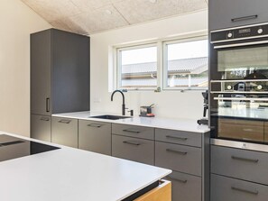 A modern kitchen with a built-in oven, a window above the sink, and a countertop. - 4 Star Holiday Home in Blavand (Blavand)