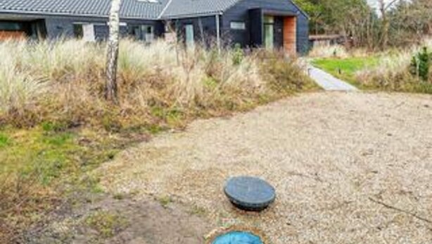 Une maison avec une allée en gravier, un objet circulaire bleu et un autre objet bleu posé sur le sol.