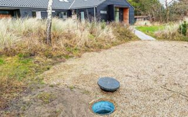Ein Haus mit einem Schotterweg, einem blauen, runden Gegenstand und einem blauen Objekt am Boden.
