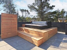 A hot tub with wooden steps and a wooden wall on a rooftop patio.