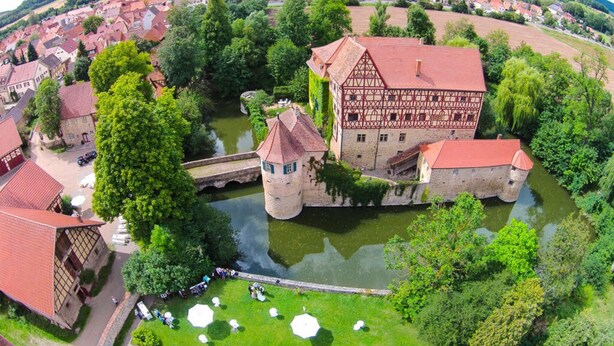 An aerial view of a historic town with a prominent half-timbered building, a river, and surrounding greenery. - Pleasant Apartment in Unsleben (Unsleben)