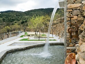 Ein Wasserspiel mit einer Steinmauer und einer alten Pump.'