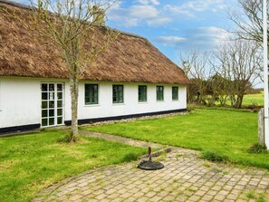 A traditional white building with a thatched roof, a paved pathway, and a grassy area. - 9 Person Holiday Home in Tim (Tim)