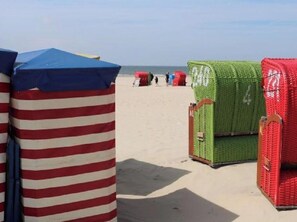 Beach huts with striped and solid colors, arranged on a sandy beach. - Borkum Ideal 71 B Comfortable Holiday Residence (Borkum)