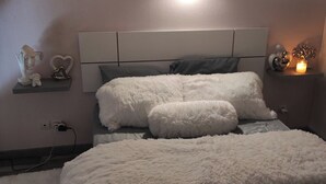 Une chambre à coucher comprenant un lit, une table de chevet, une lampe fixée au mur et des objets décoratifs.
