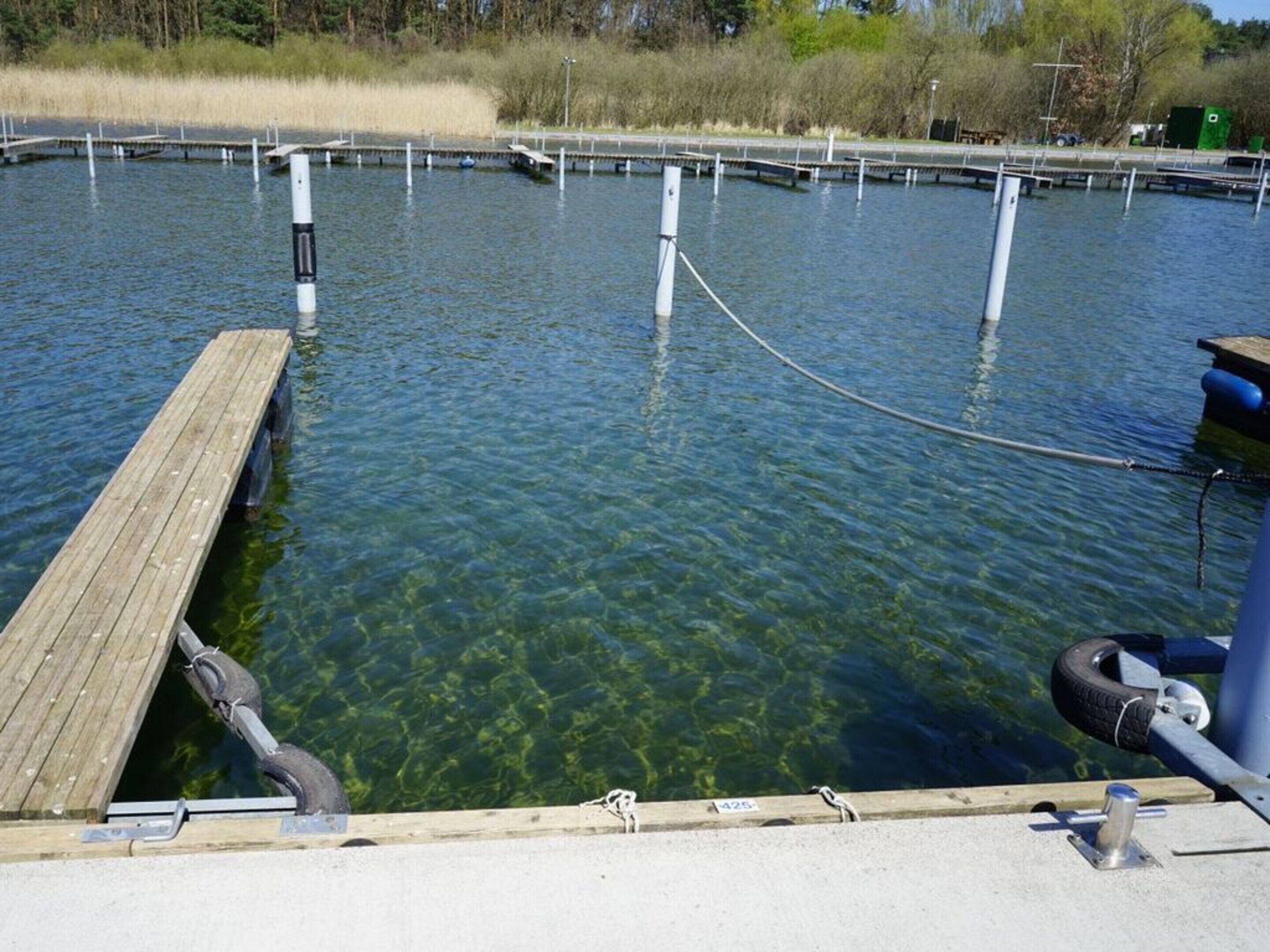 Ein klares Gewässer mit einer hölzernen Mole, die sich ins Wasser erstreckt.