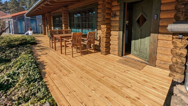Une cabane en bois dotée d’un patio couvert, d’un coin repas et d’une porte avec une poignée verte.
